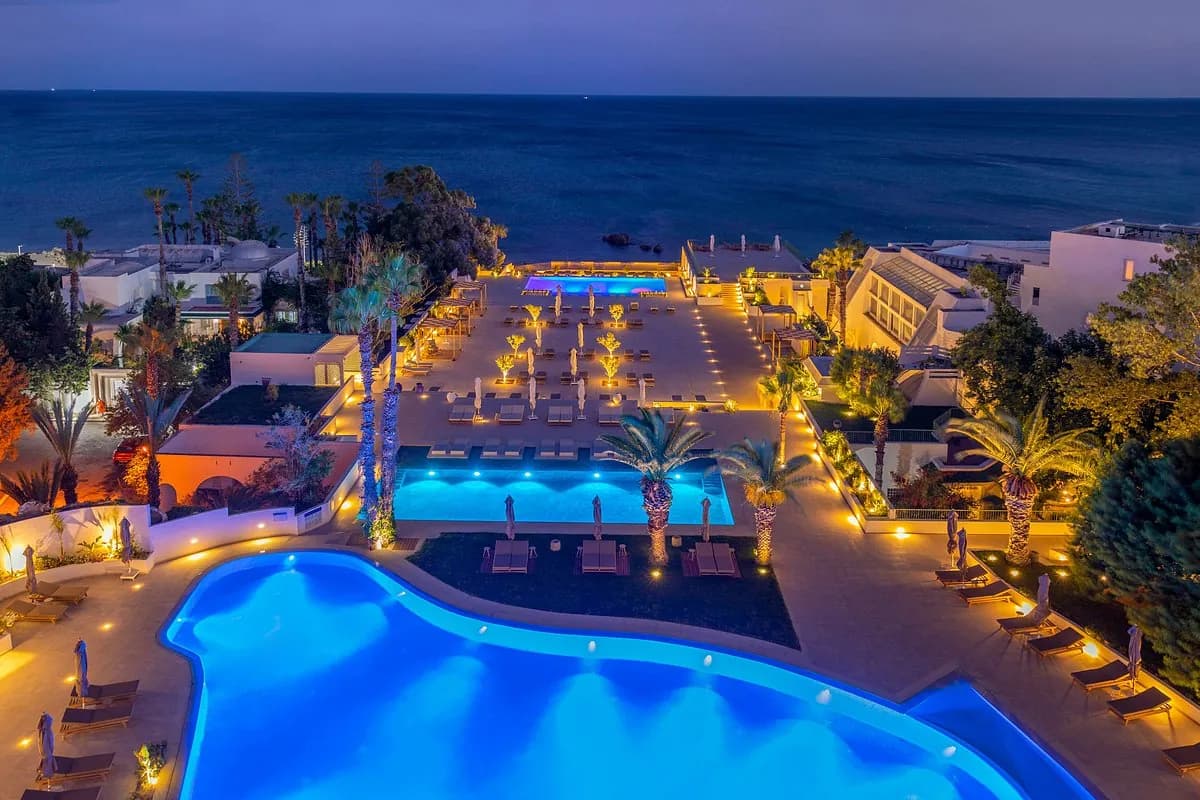 Photographie hôtelière : hôtel et piscines éclairés à la tombée de la nuit